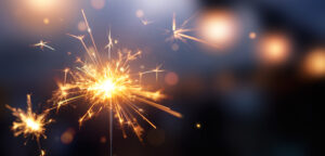 Happy,New,Year,,Glittering,Burning,Sparkler,Against,Blurred,Bokeh,Light