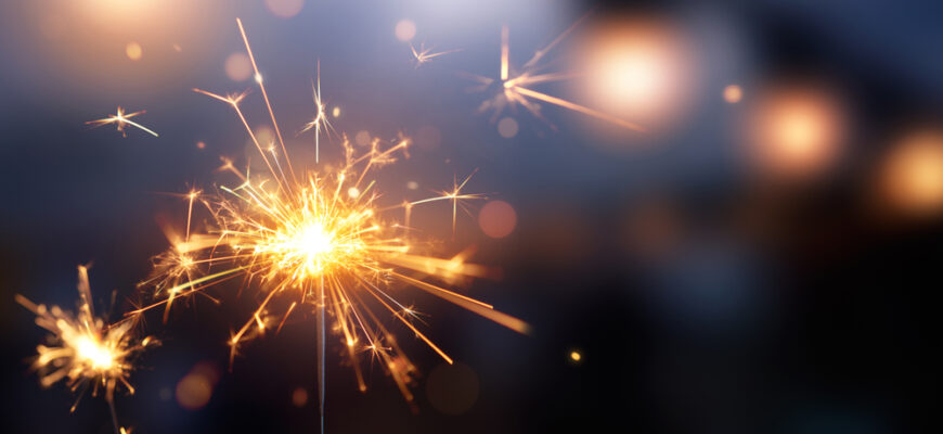 Happy,New,Year,,Glittering,Burning,Sparkler,Against,Blurred,Bokeh,Light