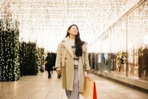 Young,Asian,Woman,Walking,Through,A,Christmas,Decorated,Shopping,Area,