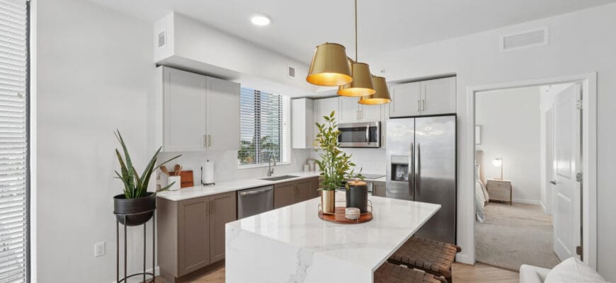 Kitchen at Evo Apartments with a kitchen island, stainless steel appliances, quartz countertops, and overhead lighting